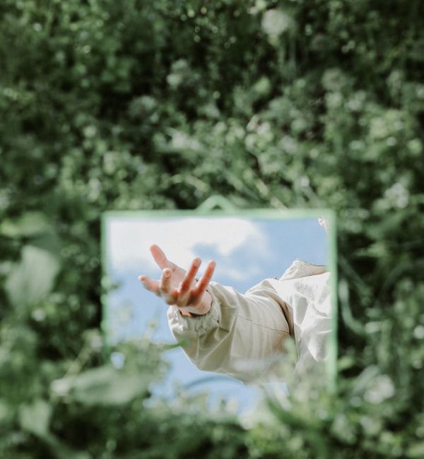 Person meditating peacefully in nature, surrounded by green foliage.